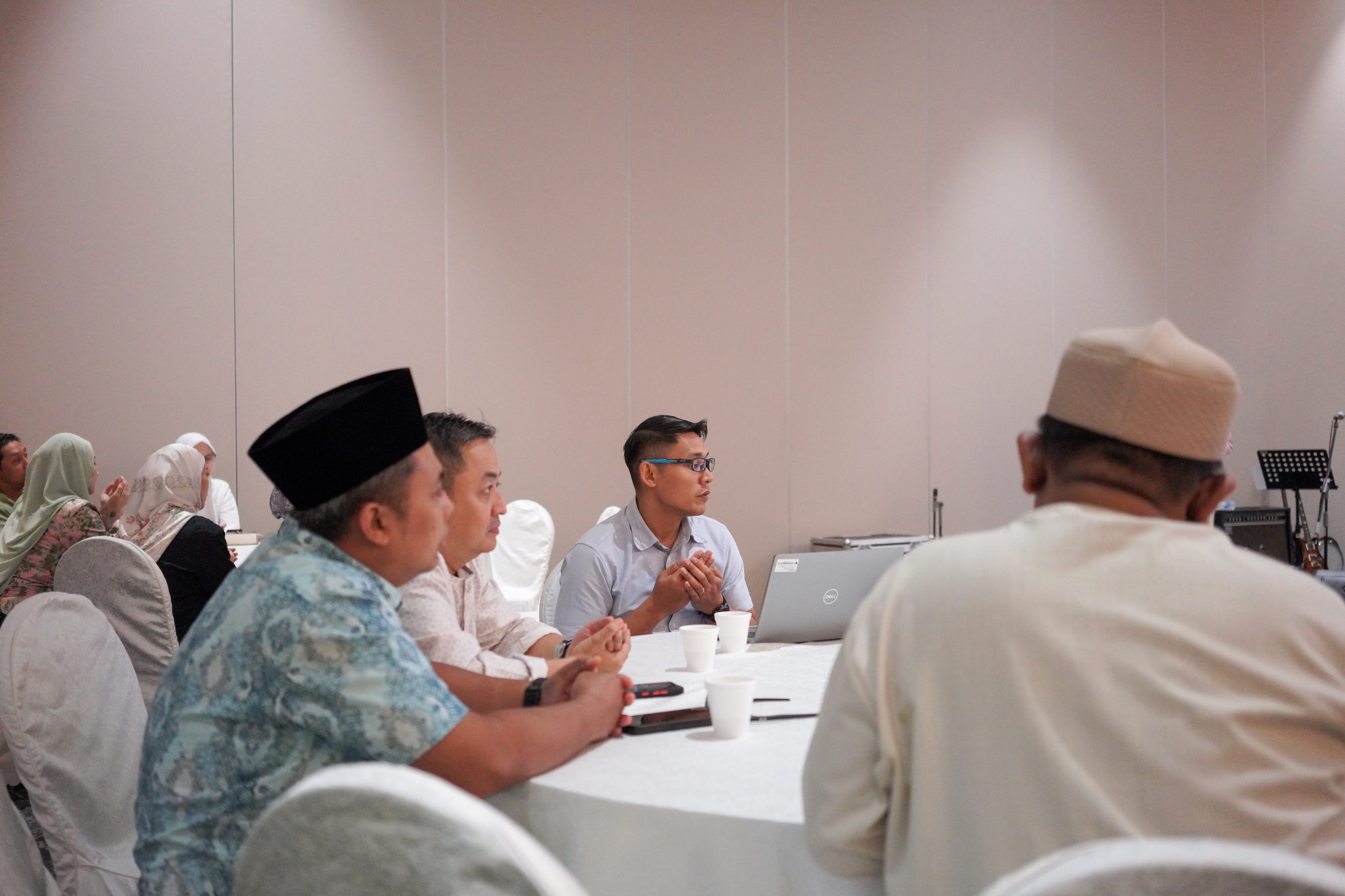 Guests seated at a table during the opening prayer before the commencement of the meeting agenda.